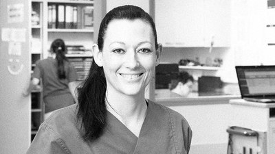 Schwarz-Weiß-Porträt von Karin Ellinger in ihrem Arbeitsumfeld, sie trägt einen Kasack.