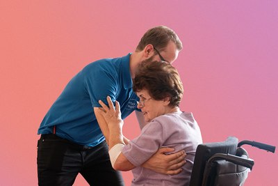 Ein Mann in einem blauen Hemd hilft einer älteren Frau im Rollstuhl. Die Frau, die ein lila Oberteil trägt, hält ihn an den Armen fest. Der Hintergrund ist ein Farbverlauf aus Rosa und Orange.