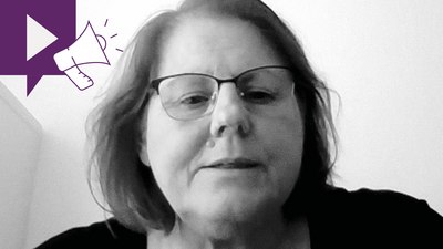 Eine Frau mit Brille und schulterlangem Haar blickt in die Kamera. Das Bild ist schwarzweiß. In der oberen linken Ecke ist die violette Grafik eines Megaphons zu sehen.