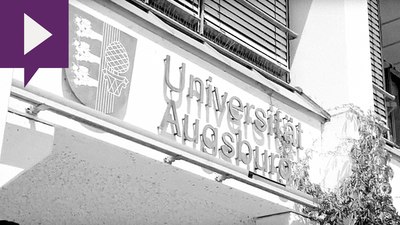 Das Logo der Universität Augsburg an einer Hauswand.