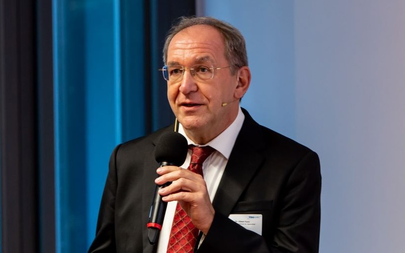 Es ist Albert Kern, Referatsleiter im Bundesgesundheitsministerium, bei einer Rede mit Mikrofon in der Hand zu sehen.